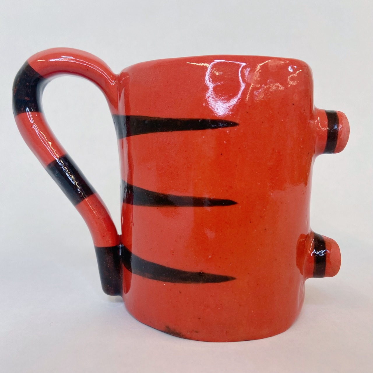 The mug laid out like how a regular mug would sit. The silhouette shows the tail handle on one side, with the feet on the other side.