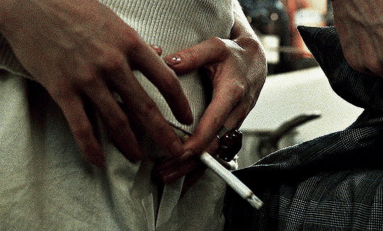 Gif #06 of 11. A woman holds a cigarette in her left hand and caresses a man's crotch area with her other hand.