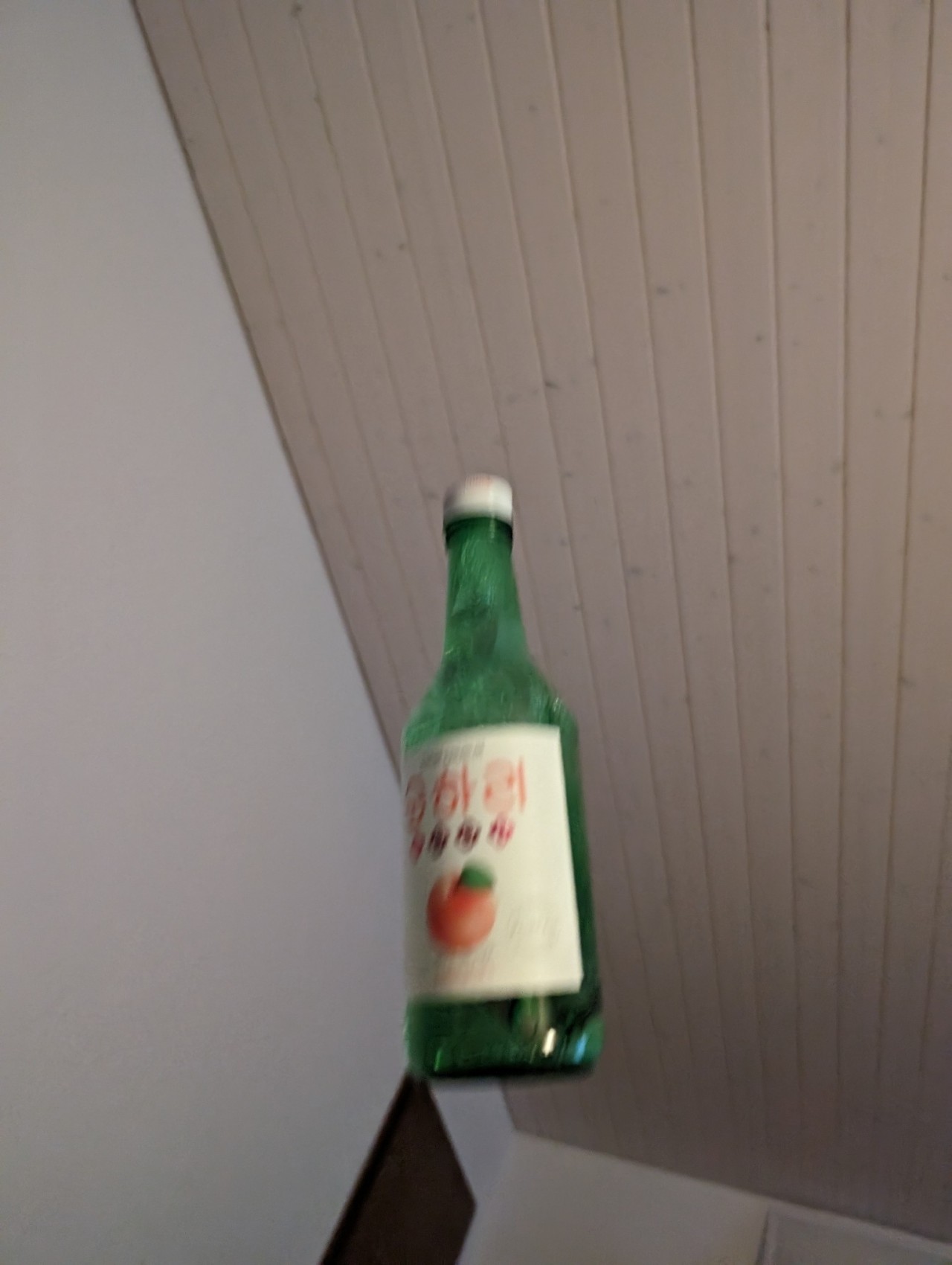 a photo of a bottle of plum soju in mid air