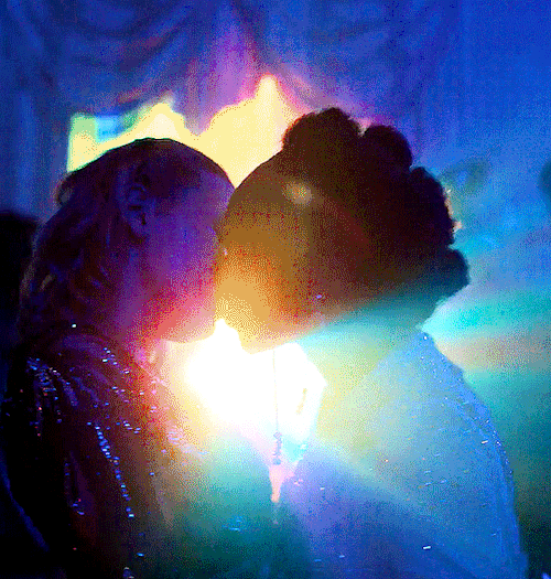 Tara and Darcy kissing at a party, lights flashing around them