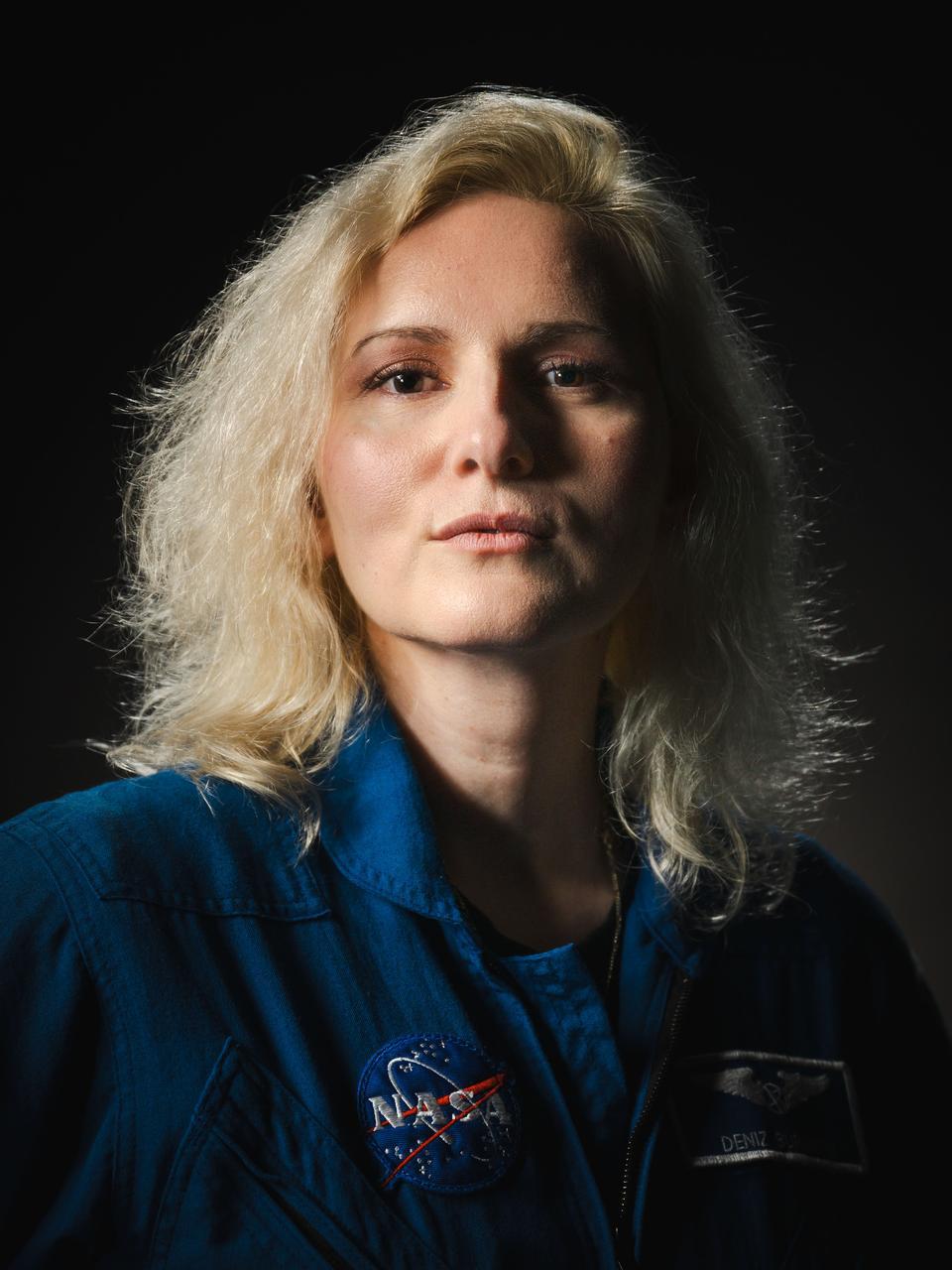 NASA astronaut Deniz Burnham, a white woman, poses for a portrait at NASA's Johnson Space Center in Houston, Texas. She looks directly into the camera as the light highlights her blonde hair. Credit: NASA/Josh Valcarcel
