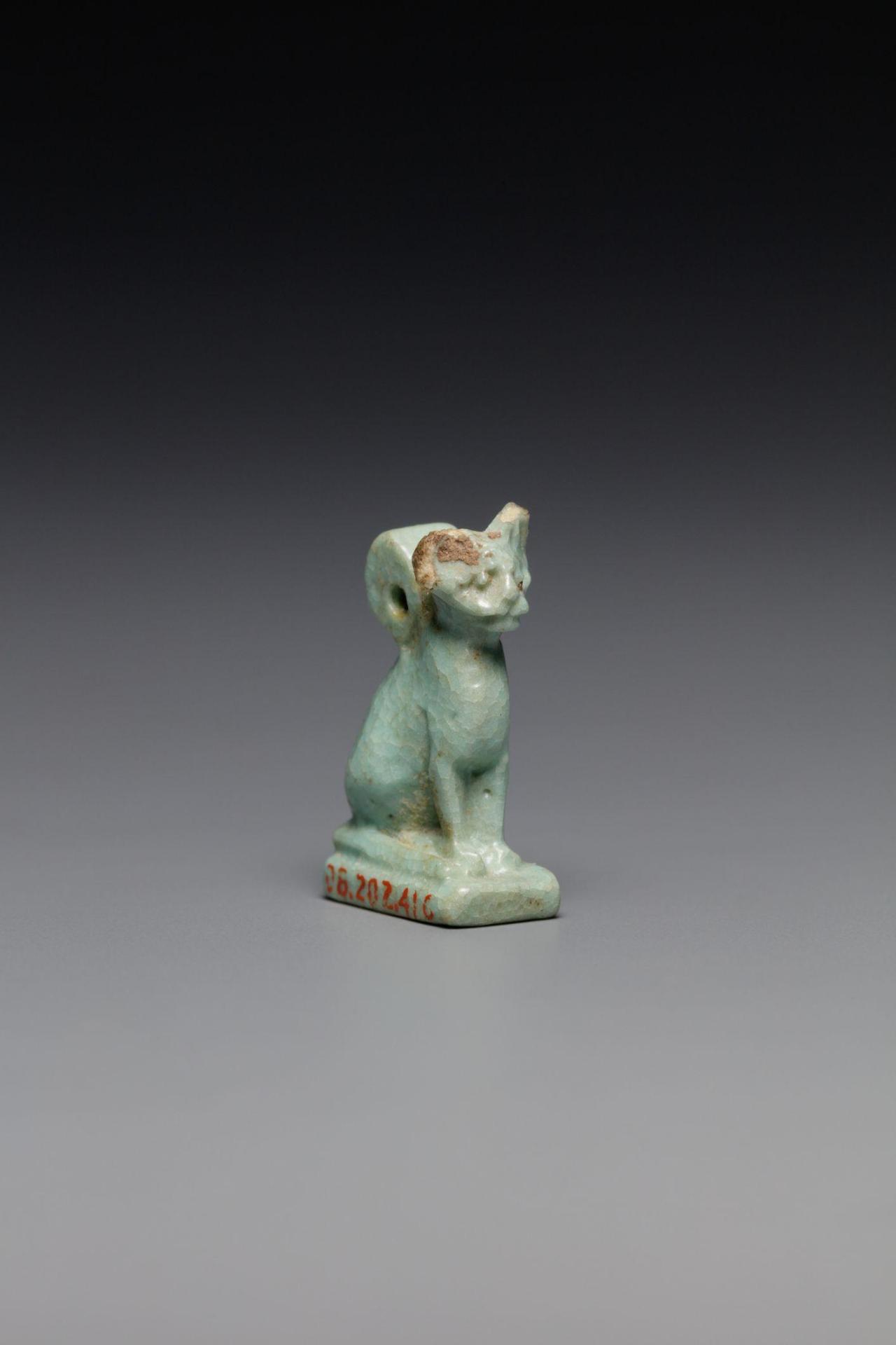 A blue amulet in the shape of a cat, with visible aging.