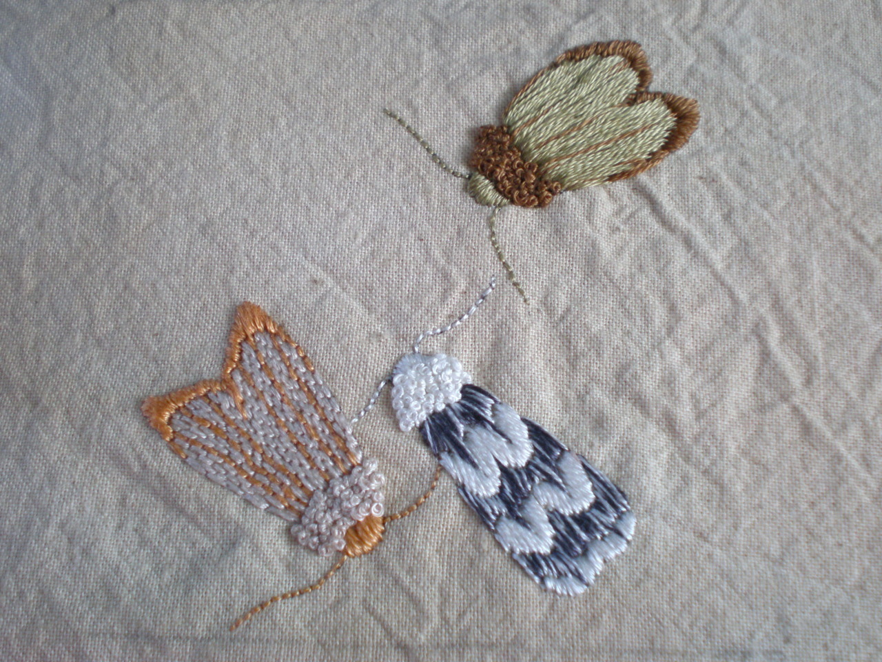Hand embroidered moths on tea-dyed cotton by Mearle of http://birdcagebox.tumblr.com/