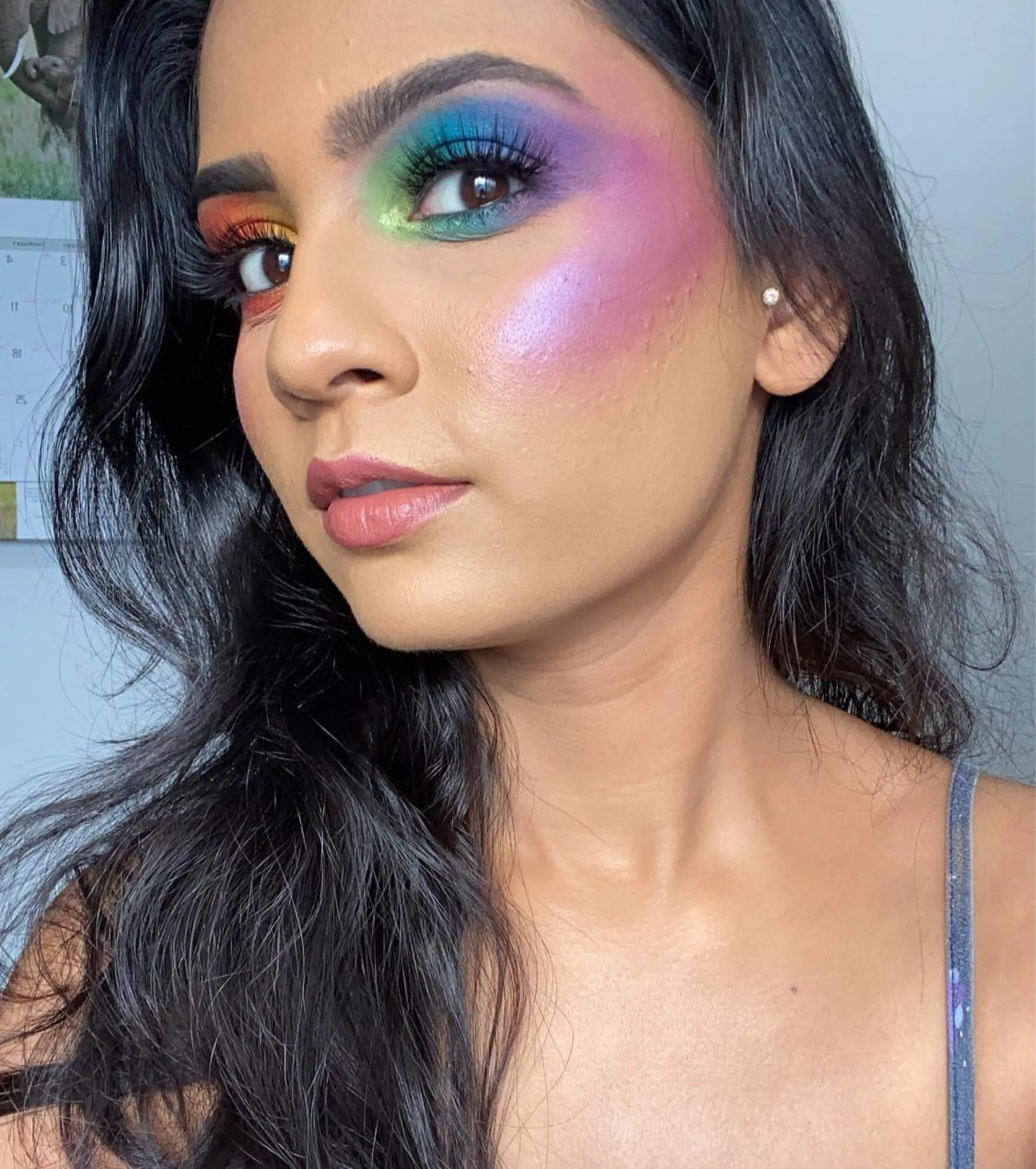 A woman with bright, rainbow colored eye makeup.