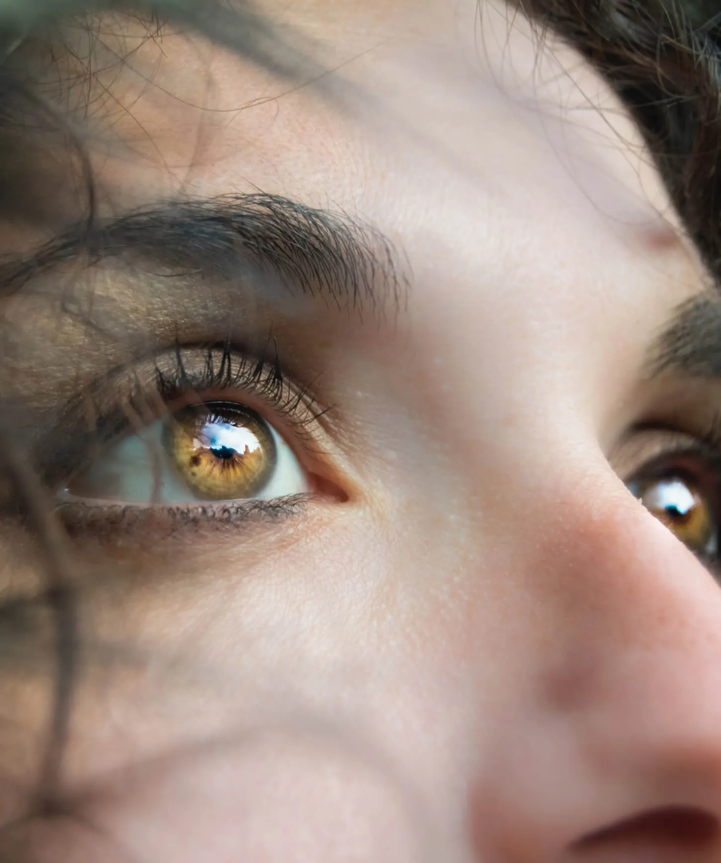 An image of a woman looking into the sky, with a close-up onto her eye