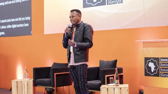 A photograph of Daniel Motaung speaking on stage.
