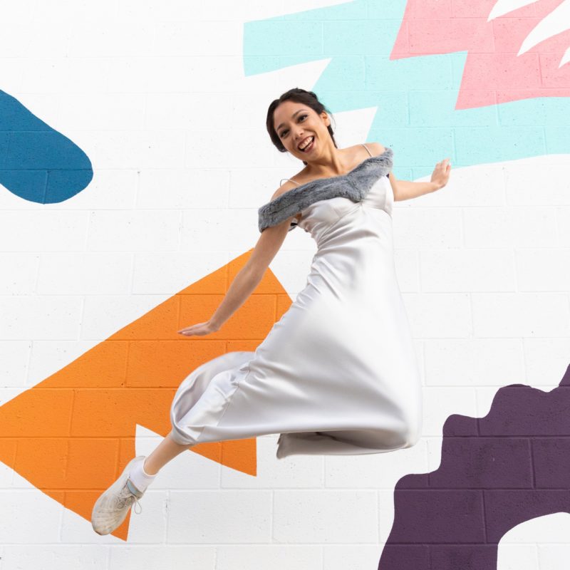 Xyla Foxlin jumps in front of a mural.