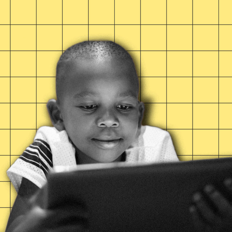 A child smiles while using a table computer.