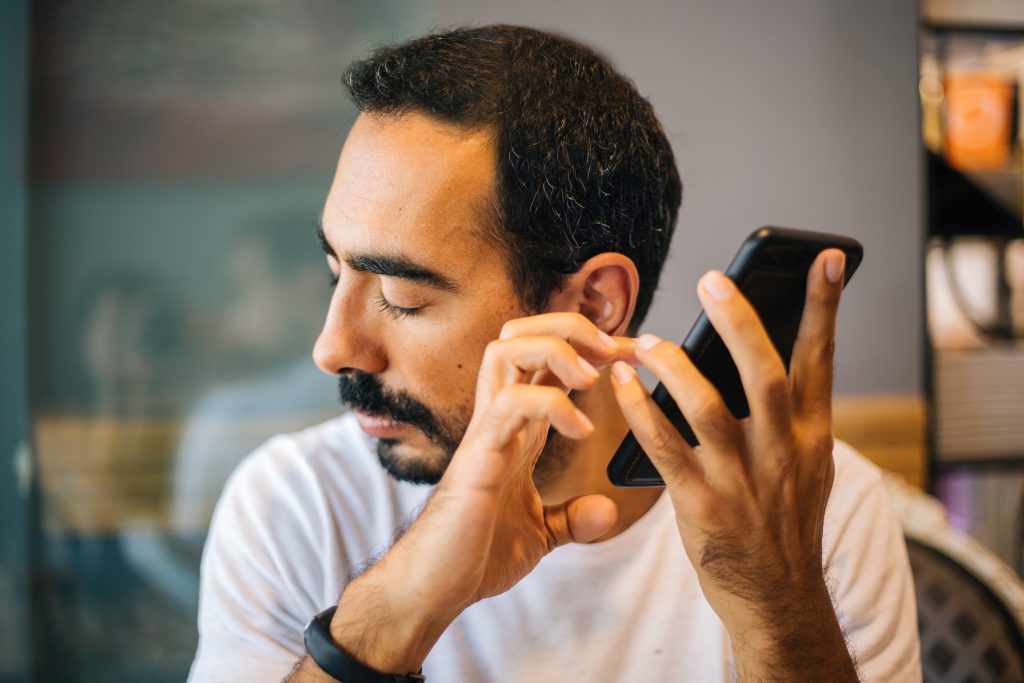 A man holds a phone near his ear with his eyes closed.