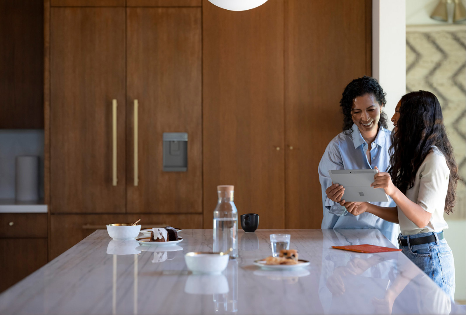 家長和小孩在廚房裡使用 Surface Go 3。