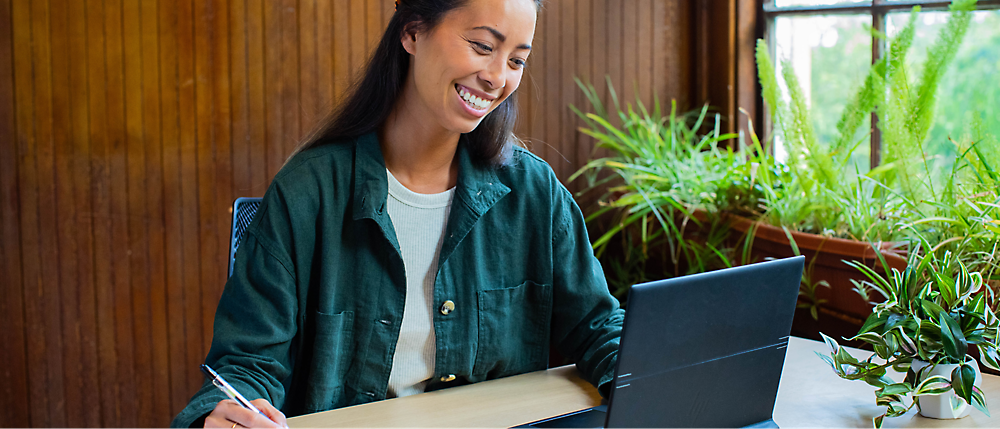 ผู้หญิงกำลังยิ้มและทำงานบนแล็ปท็อป
