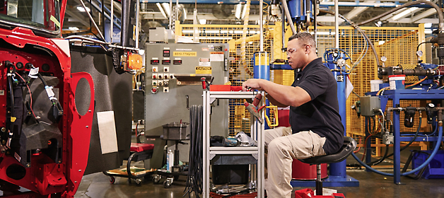Un trabajador inspecciona un componente en una estación de fabricación industrial.