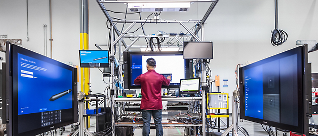 대형 모니터로 둘러싸인 첨단 실험실 환경에서 장비를 작업하는 기술자.