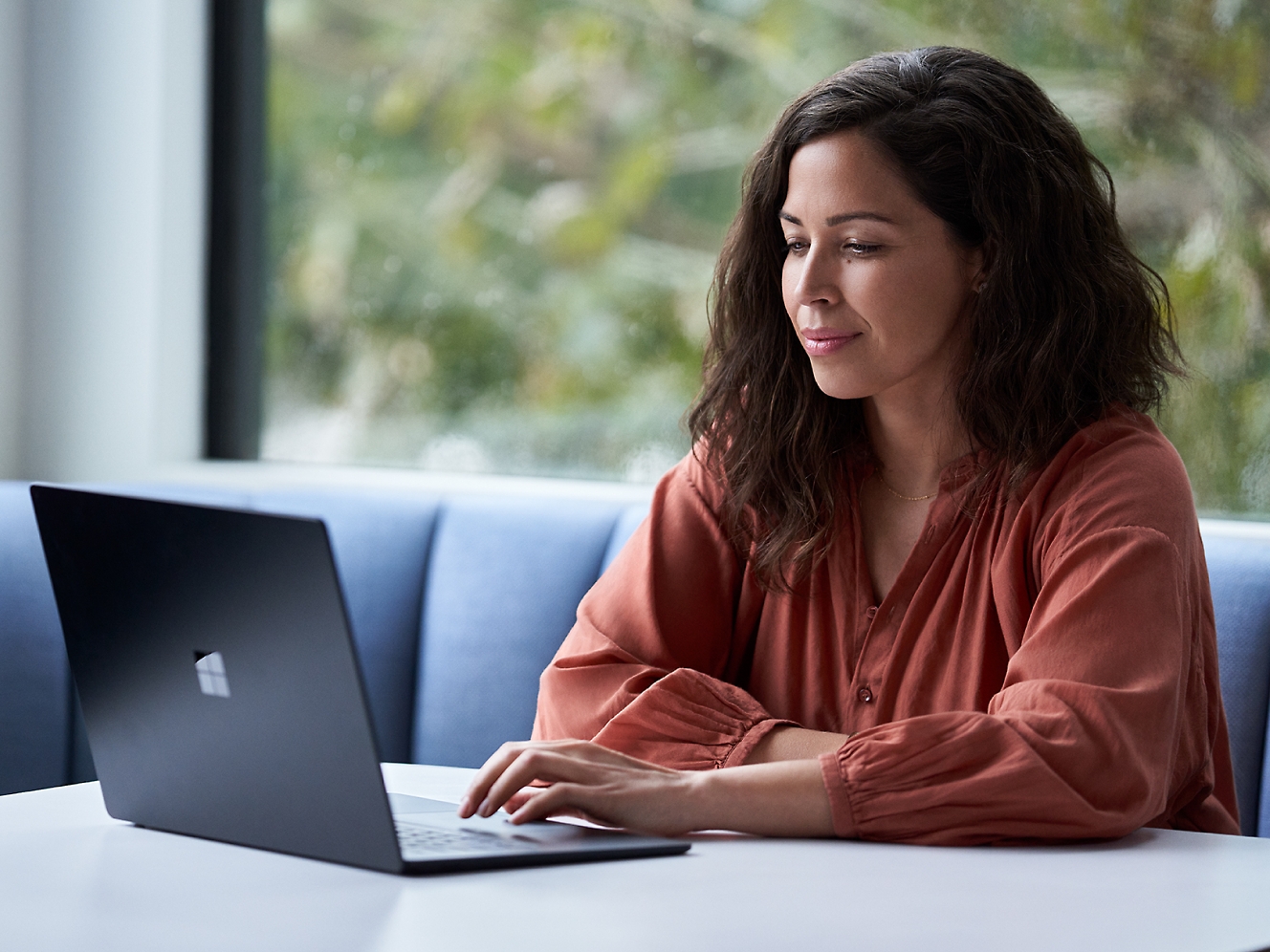 En kvinna sitter vid ett bord med en bärbar dator.