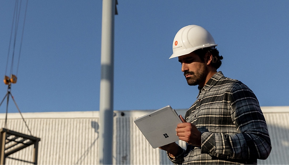 A person wearing a hard hat using a Surface device
