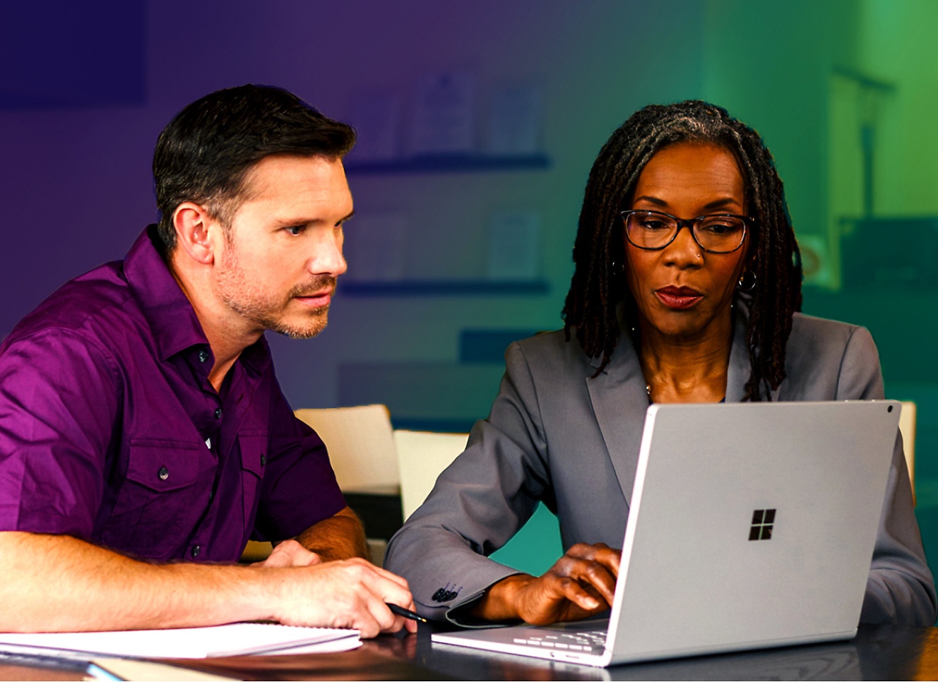 Um homem e uma mulher olhando para um laptop.