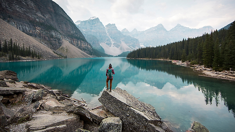 一个人站在山脉和水晶般湛蓝的湖泊前的风景