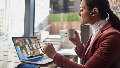 Žena pije šolju čaja i putem aplikacije Microsoft Teams učestvuje na sastanku s kolegama.