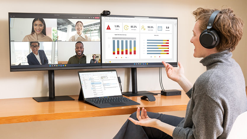 En person, der ringer ind til et møde med sin Surface Pro 9, der er forbundet til flere skærme