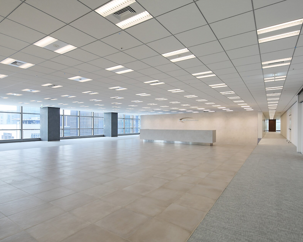 Modern, empty office space with tiled floors, white walls, and large windows letting in natural light
