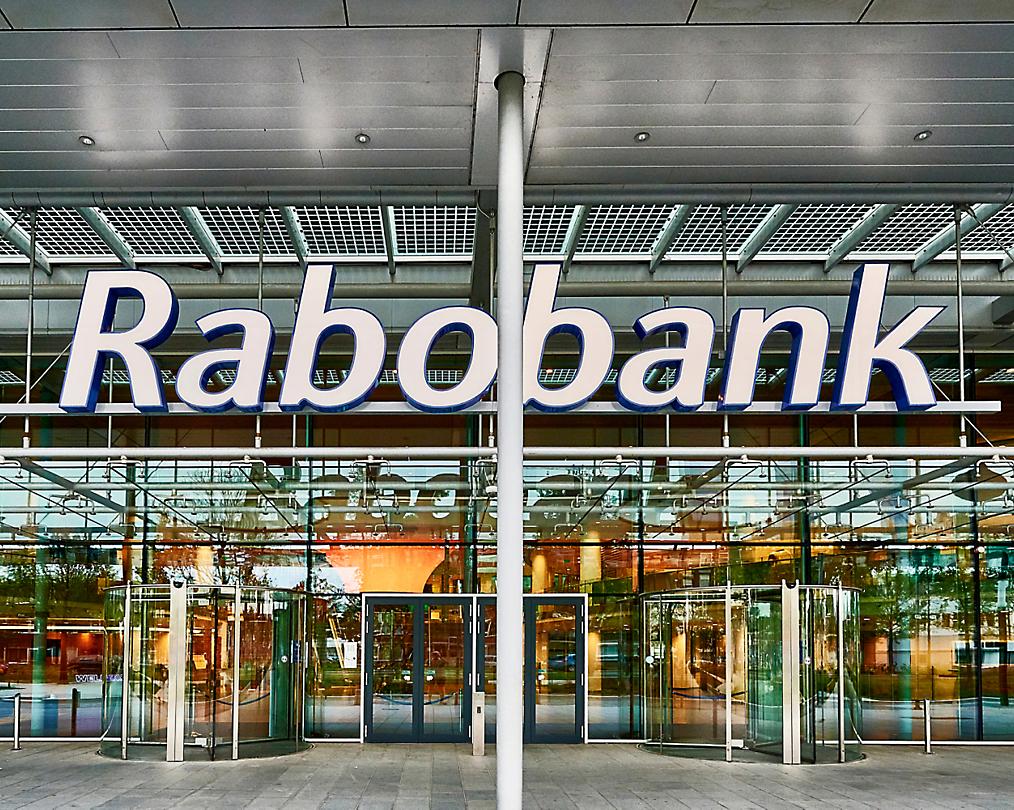 带有玻璃门的 Rabobank 大楼外景，入口上方的大型标识显示了该银行的名称。