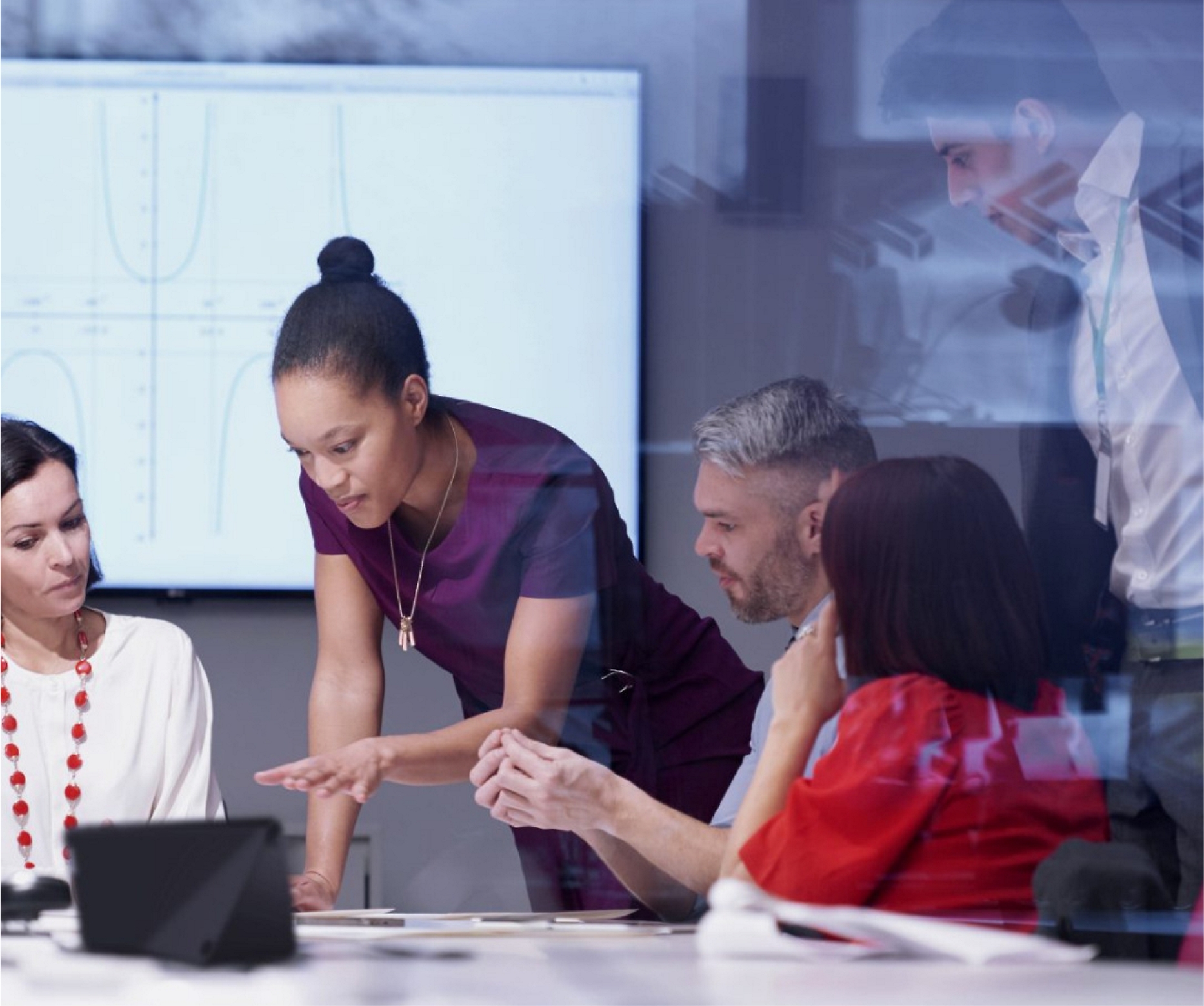 Um grupo diversificado de profissionais discutindo em torno de um laptop em um ambiente de escritório moderno.