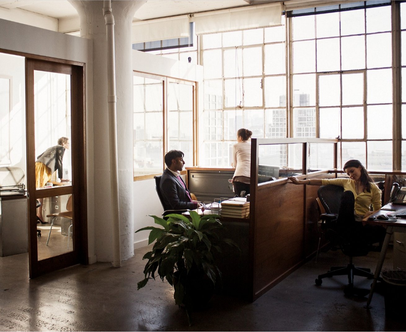Μια ομάδα ατόμων που κάθονται σε γραφεία σε ένα γραφείο.