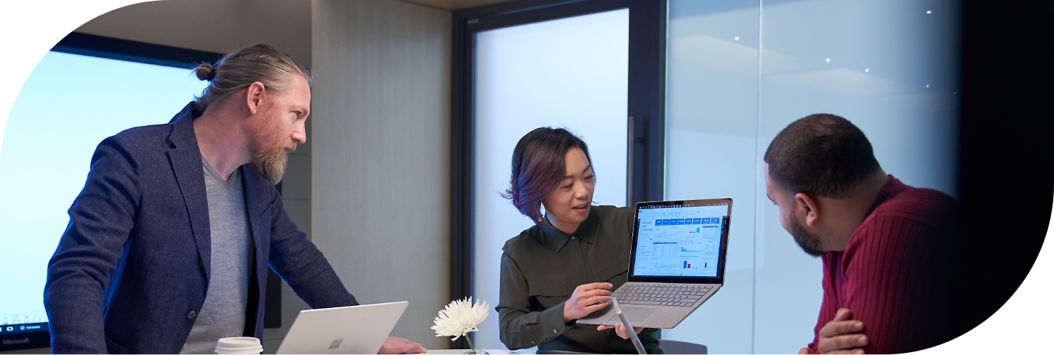 En person håller upp en bärbar dator så att två arbetskamrater kan se informationen som visas.