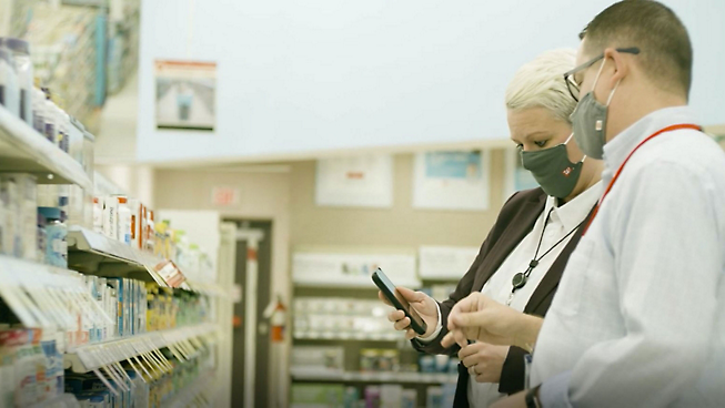 Två personer som bär masker i ett apotek.