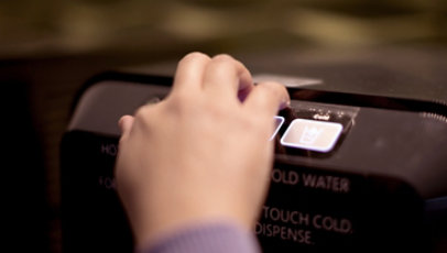 A close-up of a person's hand pushing a button.