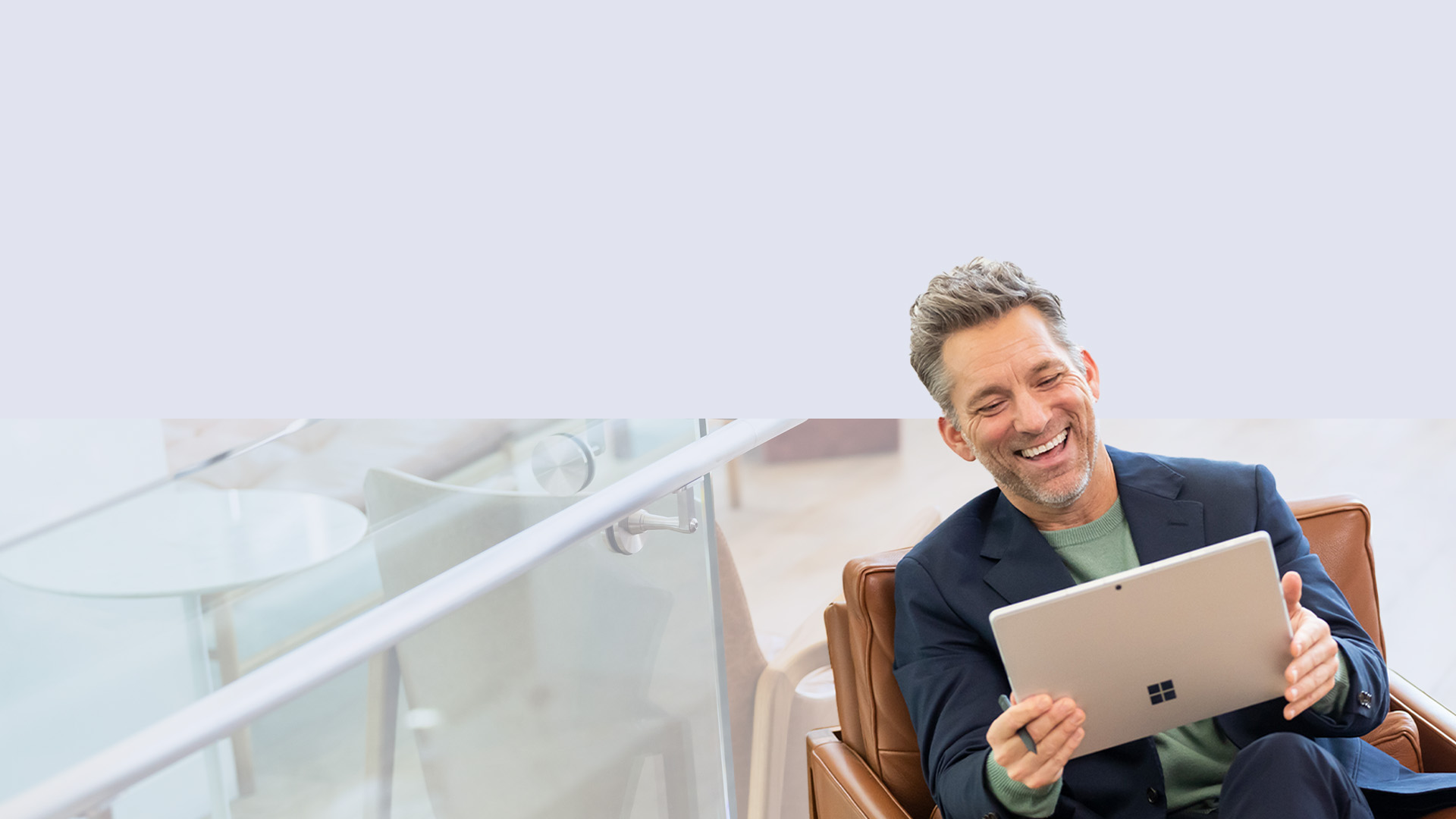 رجل جالس على أريكة ويحمل قلم Surface Slim Pen 2 في يده بينما يستمتع باستخدام جهاز Surface Pro 9‎