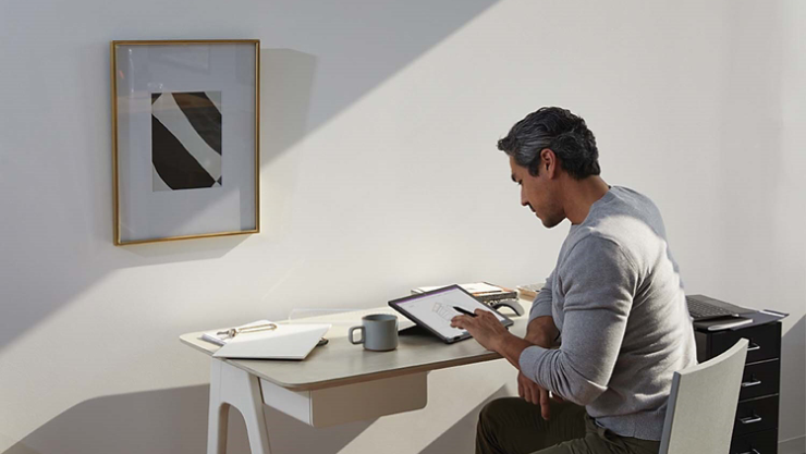 ผู้ชายคนหนึ่งใช้ปากกา Surface และ Surface Pro ในการทำงานจากโฮมออฟฟิศ