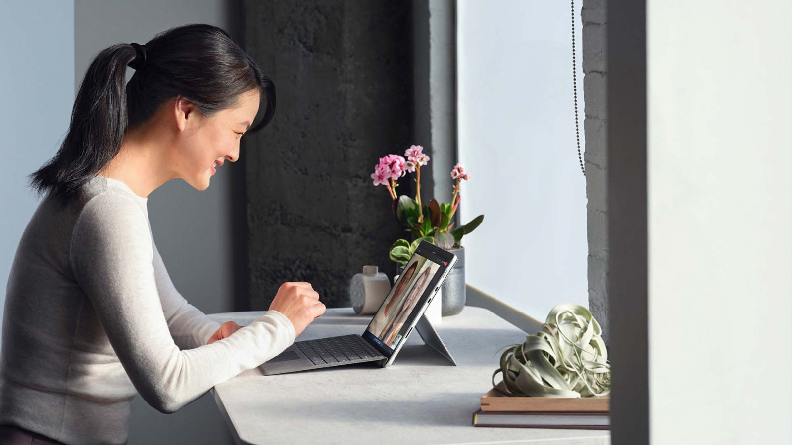 คนคนหนึ่งกำลังสนทนาผ่าน Microsoft Teams จากอุปกรณ์ Surface Pro 8 ในการตั้งค่าการทำงานจากระยะไกล