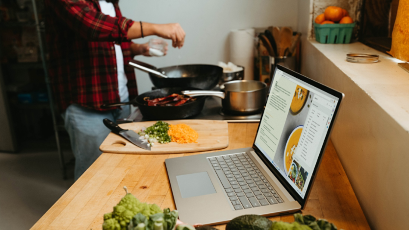 Man cooks dinner while reading a recipe in his Microsoft Edge browser