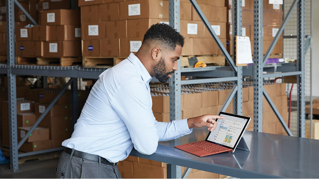 Man tijdens een videogesprek in Microsoft Teams in een magazijn. Het gebruikte apparaat is een platina Surface Pro 7+ in laptopmodus.
