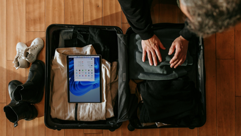 Person packing suitcase with a Surface device