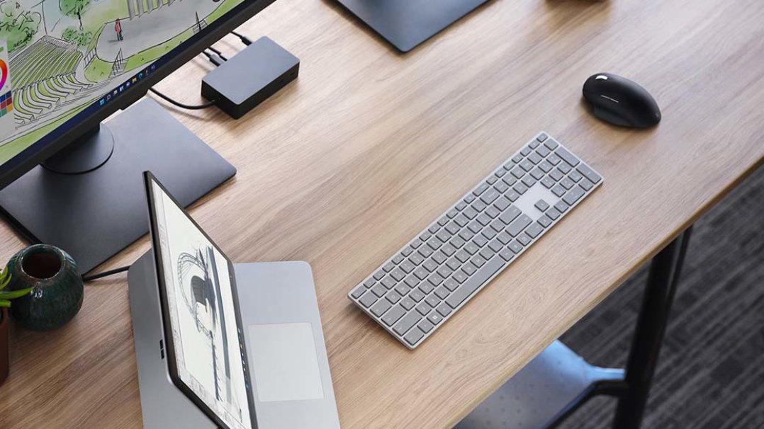 Abbildung eines Surface Laptop Studio mit verschiedenem Zubehör auf einem Büroschreibtisch