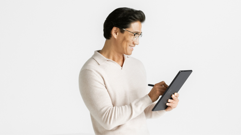 앉아서 태블릿 모드의 Surface Pro 10 제품을 들고 있는 남성