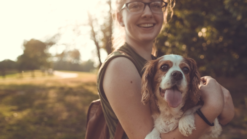 Young woman smiling with her dog outside