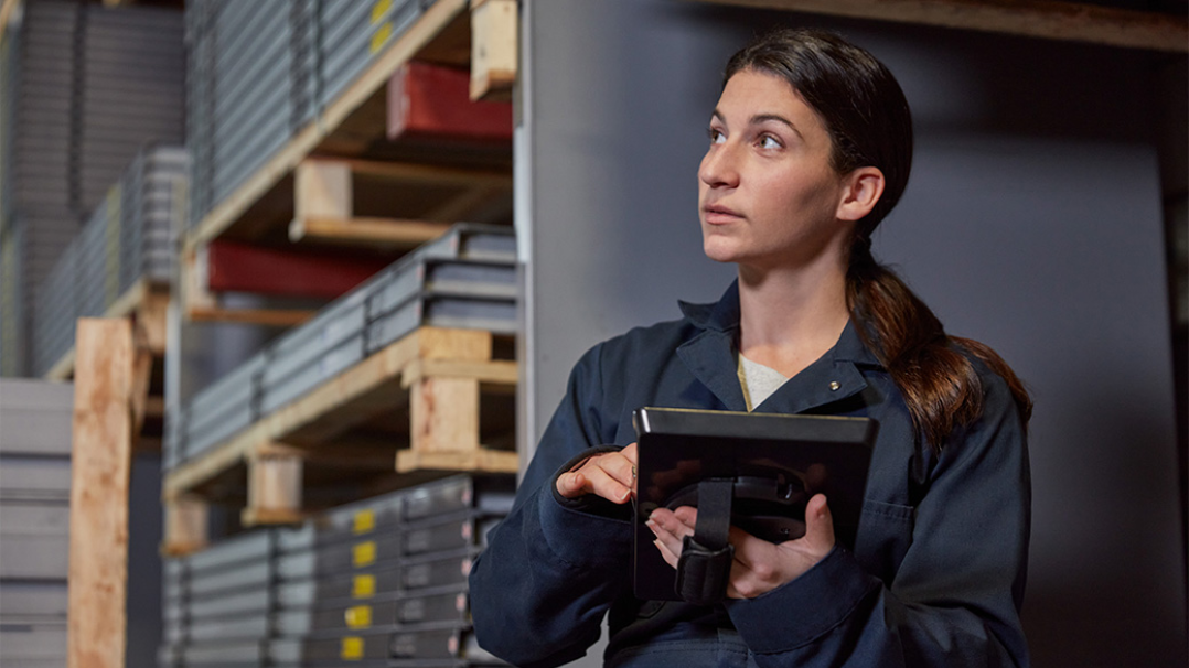 A woman holds a Surface Pro device in an industrial setting