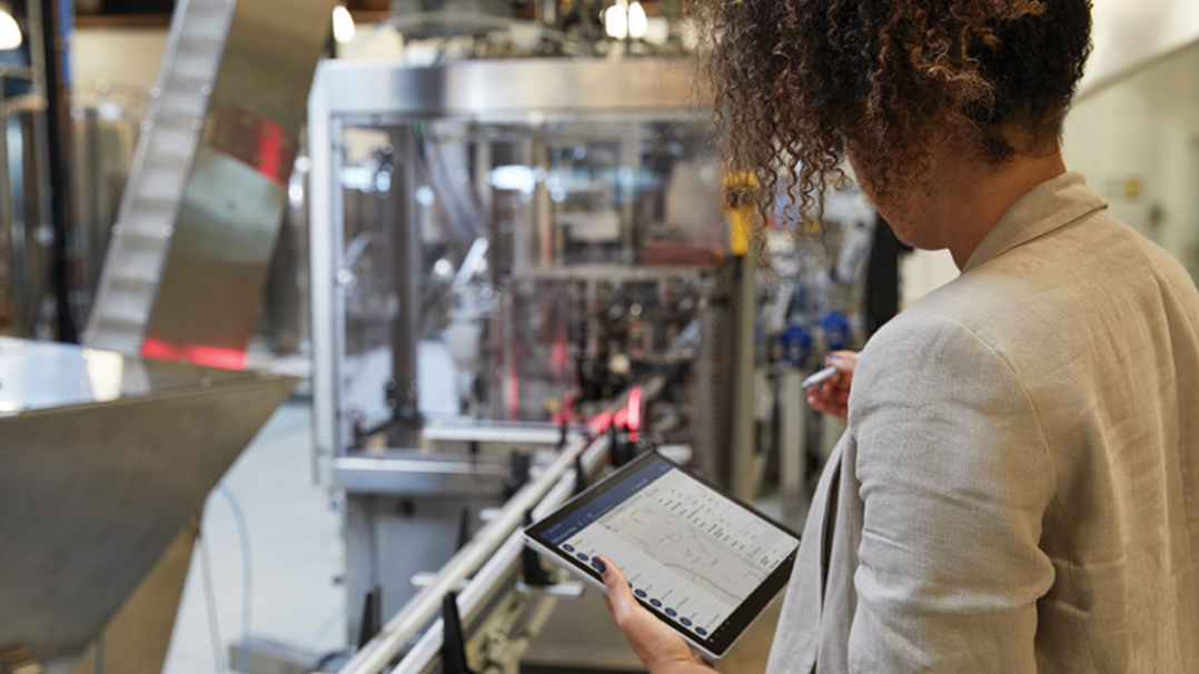 A woman is seen holding a Surface Pro device in an industrial setting