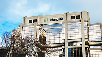 Edifício de escritórios moderno com logotipo da Manulife na fachada, em frente a um céu nublado.
