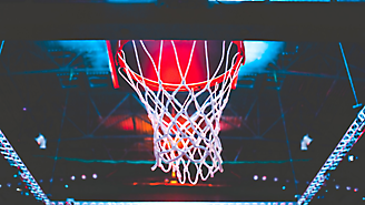 Uma cesta de basquete com uma rede, vista de baixo com um brilho vermelho no fundo