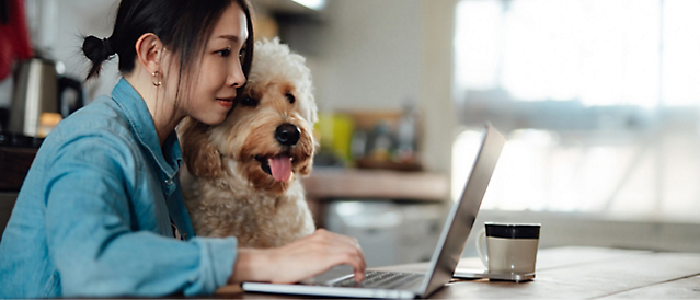 一个人在使用计算机，旁边有条狗