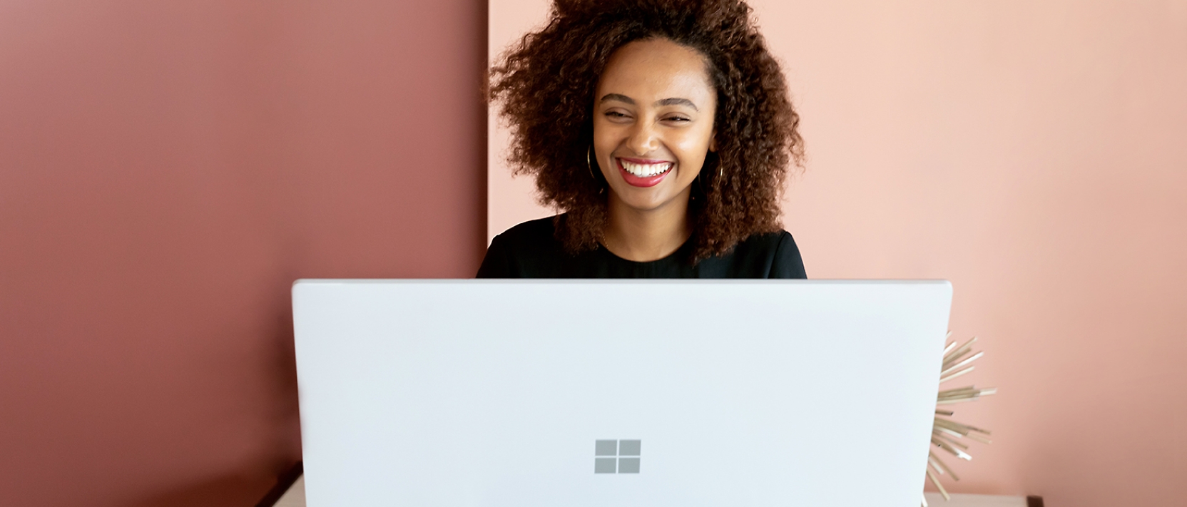 امرأة تبتسم أثناء العمل على كمبيوتر محمول.