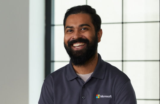 Un experto en productos para empresas de Microsoft sonríe, listo para ayudar. 