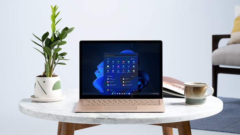 A Surface Laptop on a table with Windows 11 and other icons.