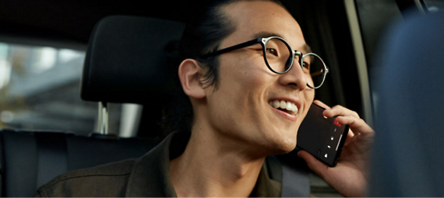 A person inside a car, wearing glasses and talking on a phone 