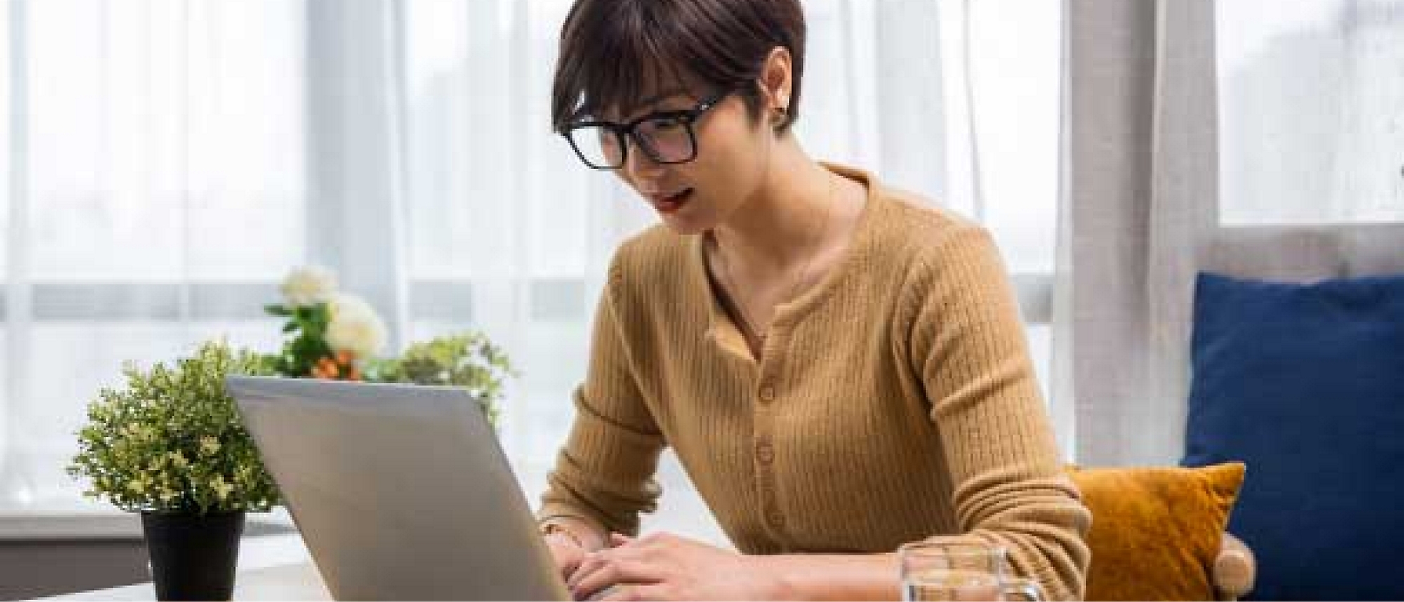 En kvinde sidder ved et bord og bruger en bærbar computer.
