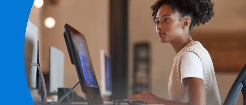 一名年輕女士在辦公室環境的桌上使用雙電腦螢幕專心工作。